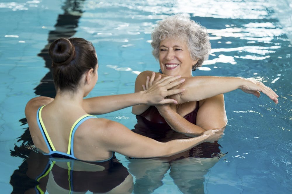 Physical therapist performing aquatic therapy with an older woman in pool