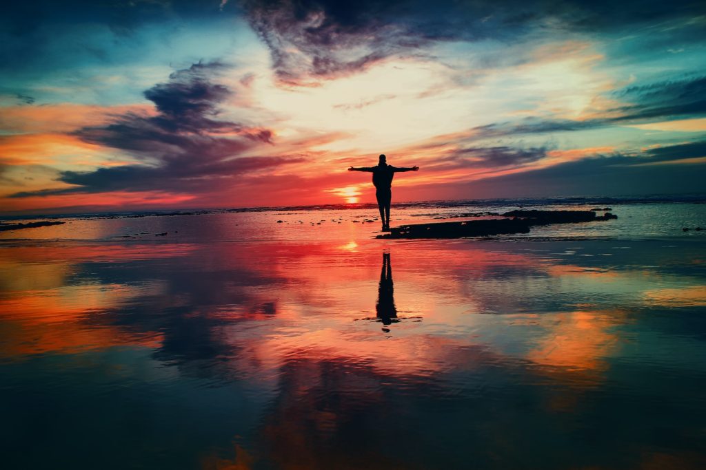 Person standing with their arms outstretched during sunset