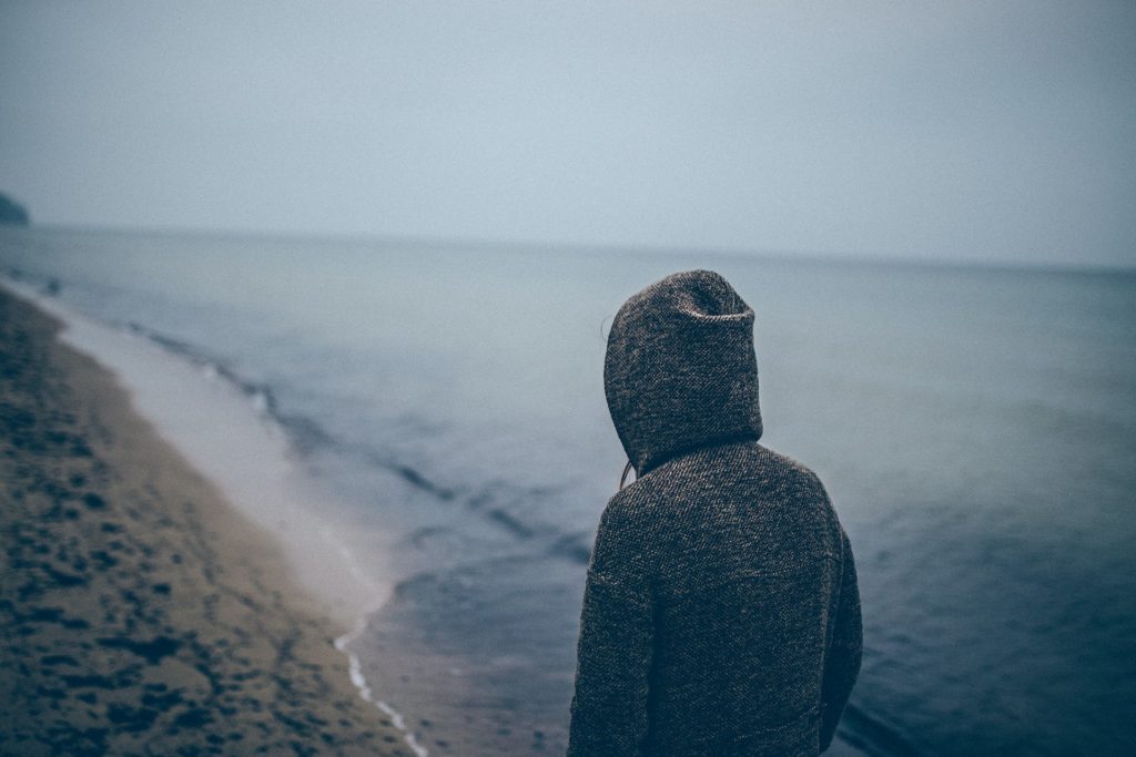 Woman walking on a beach under overcast skies